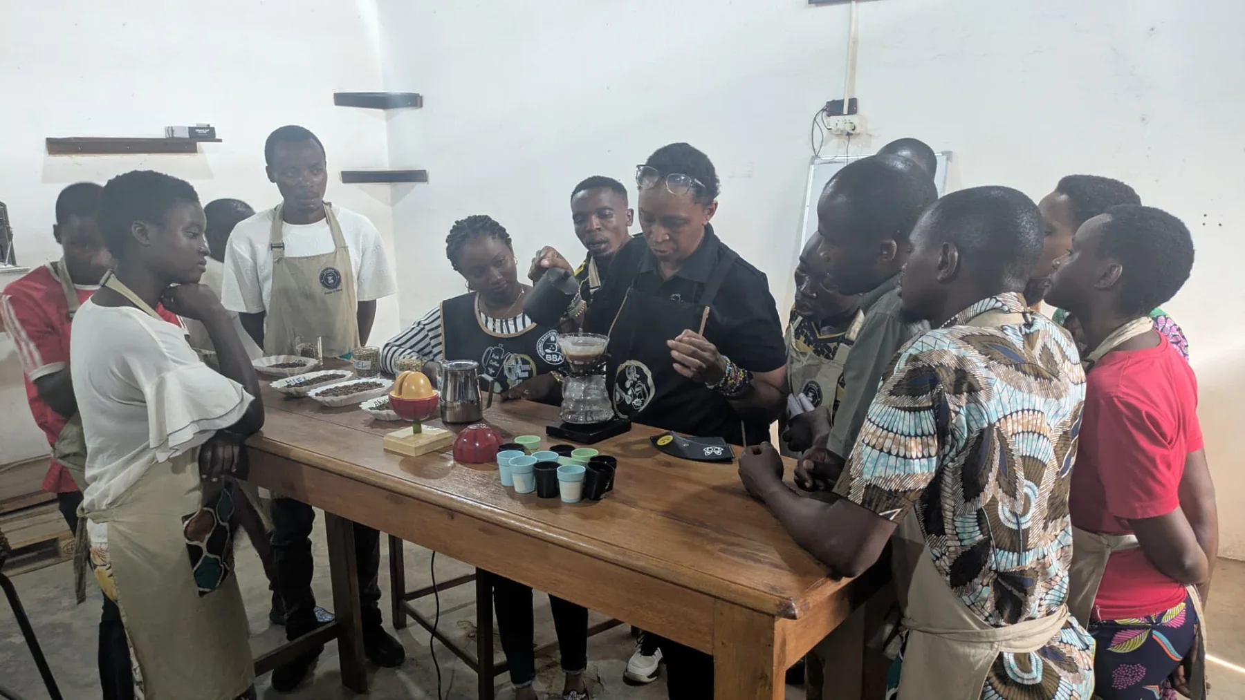 Kawasili barista trainees gathered around a pour-over coffee demonstration at Shamba Kahawa