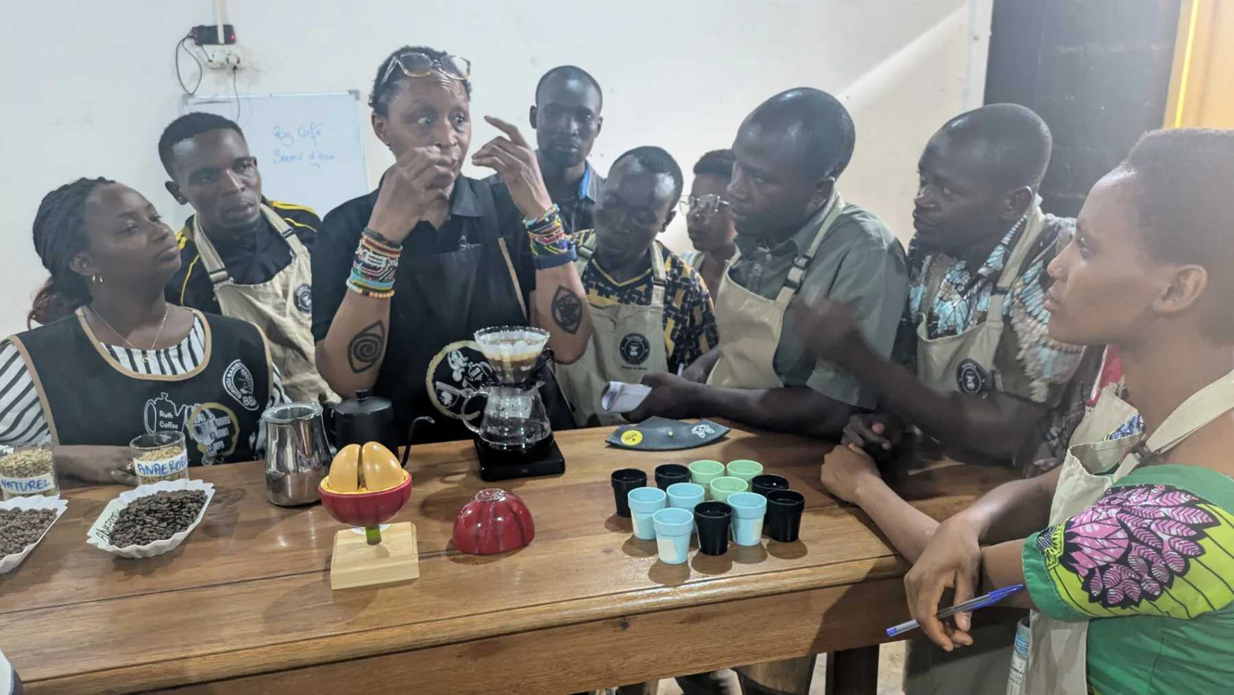 Kawasili trainees discussing coffee preparation during a hands-on learning session at Shamba Kahawa